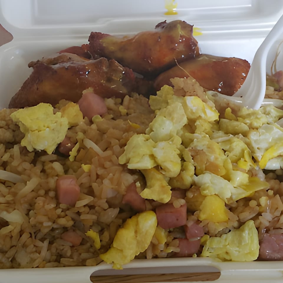 Taste of China Hut's fried rice with scrambled egg, ham, and chicken wings in a takeout container.