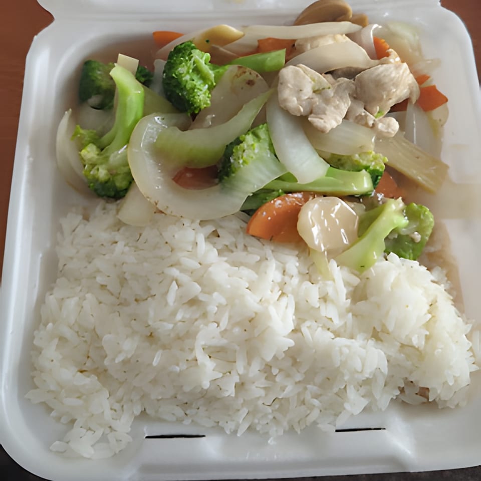 Chicken and mixed vegetables with broccoli, carrots, and onions, served with white rice in a takeout container.