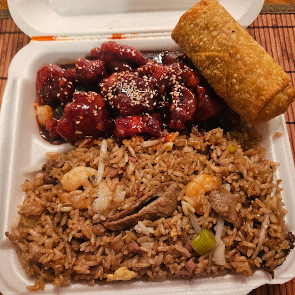 Taste of China Hut's sweet and sour chicken, fried rice, and an egg roll in a takeout container.